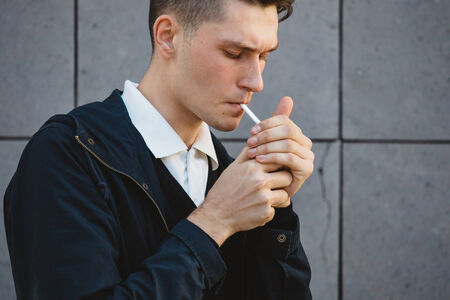 Fashion hipster male model smoking cigarette on the streetの写真素材
