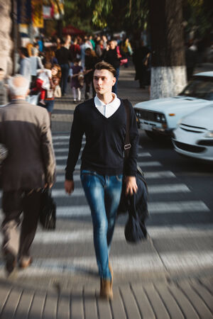 Young man cross the street at a crosswalkの写真素材