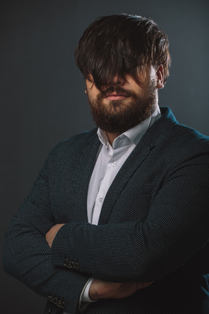 Portrait of hairy man in a jacket on black backgroundの写真素材
