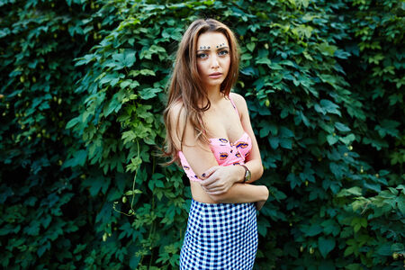 Girl with an unusual make-up posing near the wall of leavesの写真素材