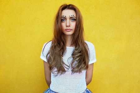 Attractive girl in an unusual skirt posing near a yellow wallの写真素材