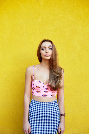 Attractive girl in an unusual skirt posing near a yellow wallの写真素材