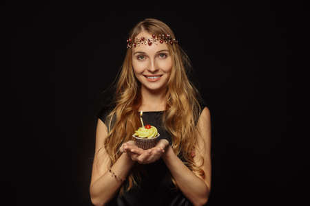 Attractive girl with a crown on her head in a white black is holding cupcakeの写真素材