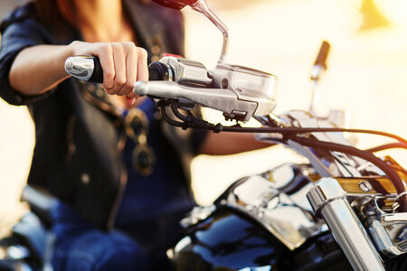 Biker girl in a leather jacket on a motorcycle. Close-up of hand