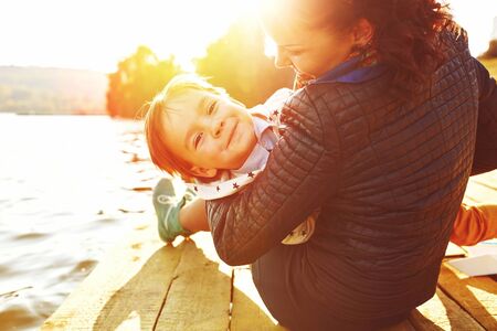 Mom and son having fun by the lake. Warm filter and film effectの写真素材