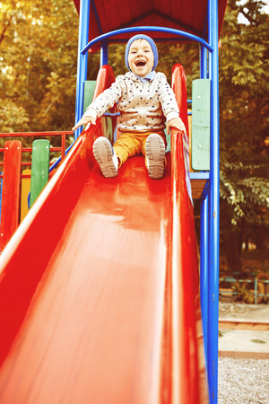 Little boy playing on children's slides. Warm filter and film effectの写真素材