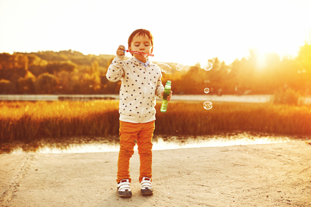 Little boy playing with soap bubbles. Warm filter and film effectの写真素材