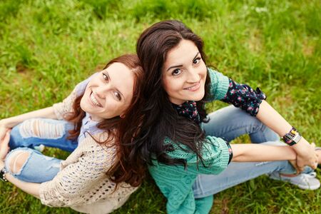 Two cheerful sisters hugging in the parkの写真素材