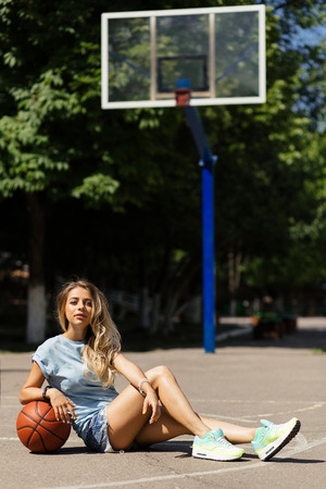 Sexy girl on the basketball court. Posing and playing with a basketball ballの写真素材