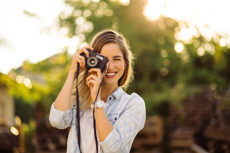 Hipster woman taking photos with retro film camera