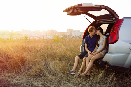 Young couple in love. Sitting in the trunk of an SUVの写真素材