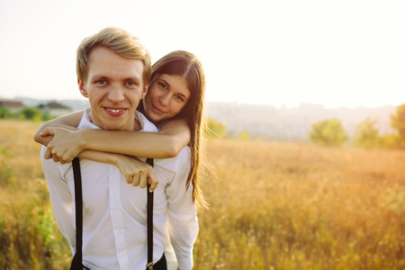 Young couple in love walking in a field at sunsetの写真素材