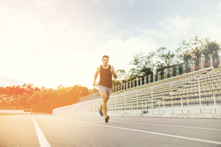 Athletic man running on a racing track