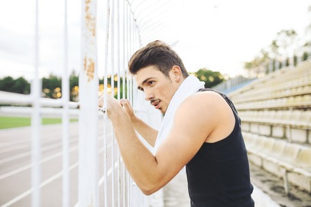 Jogger resting after running. Man runner taking a break during training outdoors. Young Caucasian...