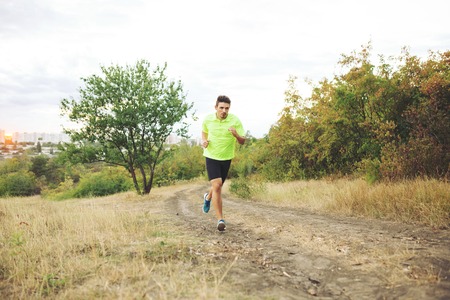 Athletic man running in the park on sunset