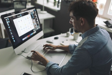 Modern designer sitting in front of computer and working in office