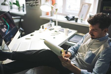 Designer at work in office. Man drawing in note pad