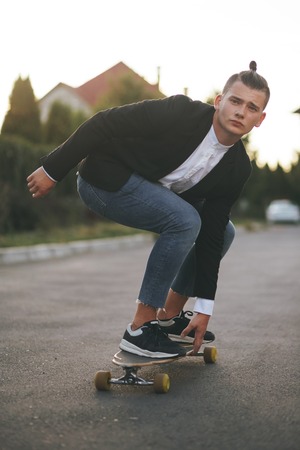 Vintage image of a man with longboard going on road,hipster young teen boy, sunset lights,mans...