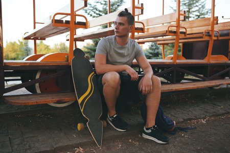 Vintage image of a man with longboard going on road,hipster young teen boy, sunset lights,mans...