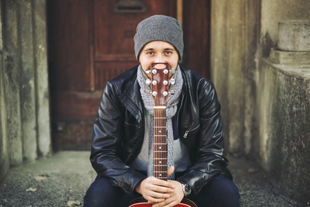 Portrait of young attractive street artist with his guitar
