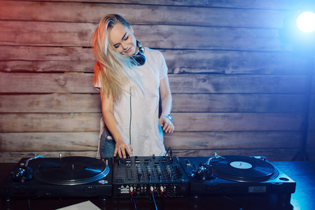 Cute dj woman having fun playing music on vinyl record deck at club party nightlife lifestyleの写真素材