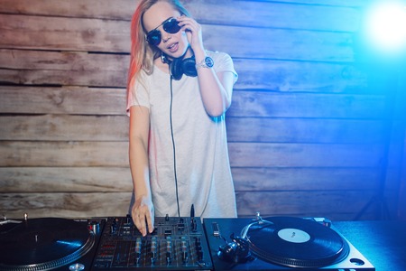 Cute dj woman having fun playing music on vinyl record deck at club party nightlife lifestyleの写真素材