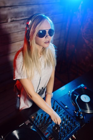 Cute dj woman having fun playing music on vinyl record deck at club party nightlife lifestyleの写真素材