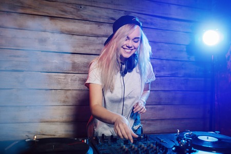 Cute dj woman having fun playing music on vinyl record deck at club party nightlife lifestyleの写真素材