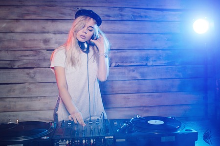Cute dj woman having fun playing music on vinyl record deck at club party nightlife lifestyleの写真素材