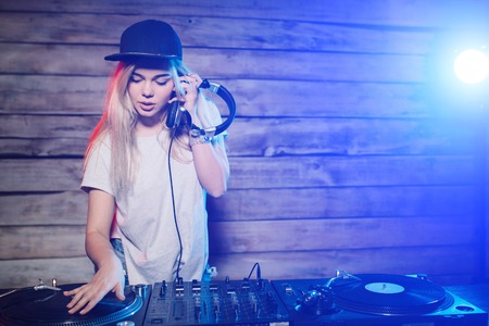 Cute dj woman having fun playing music on vinyl record deck at club party nightlife lifestyle