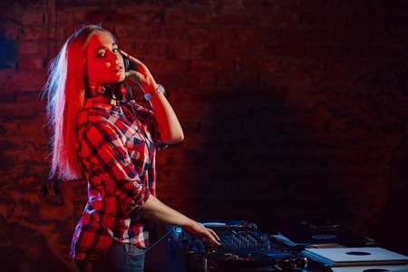 Cute dj woman having fun playing music on vinyl record deck at club party nightlife lifestyleの写真素材