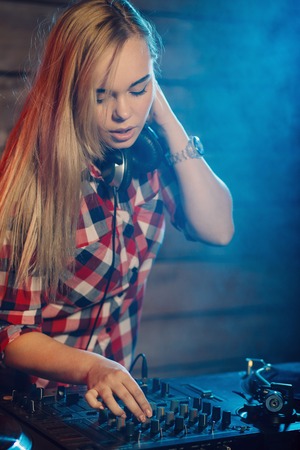 Cute dj woman having fun playing music on vinyl record deck at club party nightlife lifestyleの写真素材