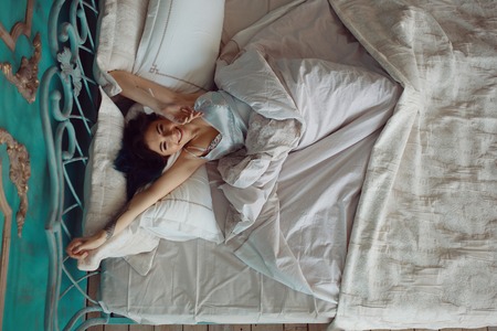 Woman stretching in bed after wake up, top viewの写真素材