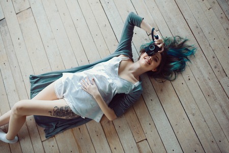 Beautiful carefree young casual woman lying on the wooden floor. Top viewの写真素材