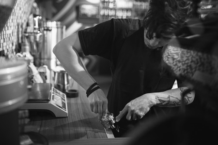 Barista at work in a coffee shop. Preparation service concept. Black and white photoの写真素材