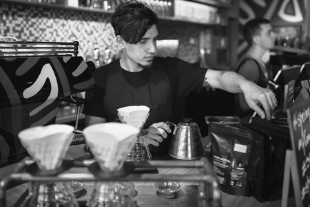 Barista at work in a coffee shop. Preparation service concept. Black and white photoの写真素材
