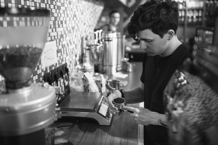 Barista at work in a coffee shop. Preparation service concept. Black and white photoの写真素材