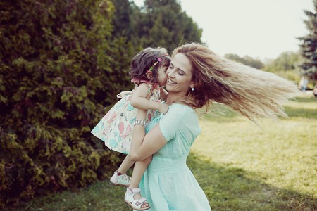 Beautiful happy mother and daughter laughing together outdoorsの写真素材