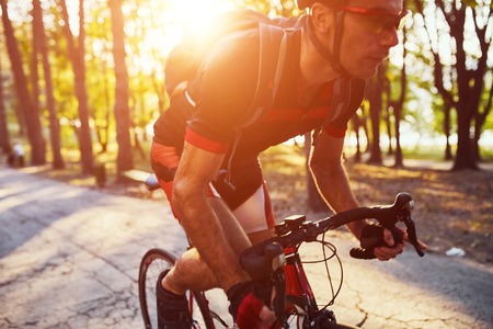 Young man are cycling road bike by the lake in the parkの写真素材