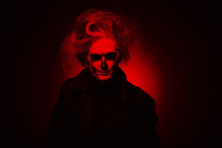 Portrait man with Halloween skull makeup. Halloween or horror theme. Red filterの写真素材