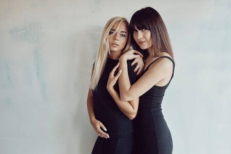 Portrait of two pretty woman in a black dress posing in an unfinished indoor.の写真素材