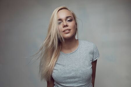 Portrait of pretty blonde woman posing in light room with light from window.の写真素材