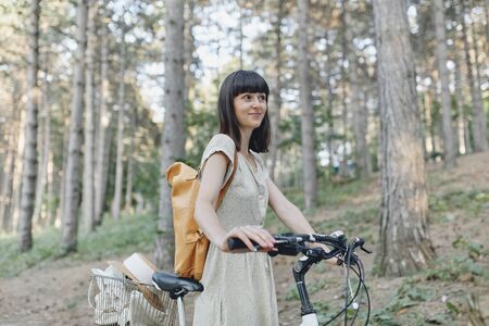 Young hipster woman against nature background with bikeの写真素材