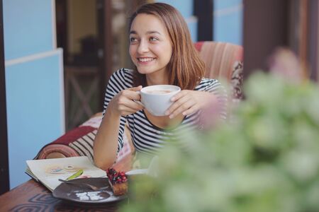 Young woman sitting indoor in urban cafe. Cafe city lifestyle. Casual portrait of teenager girlの写真素材