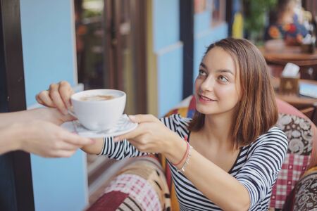 Young woman sitting indoor in urban cafe. Cafe city lifestyle. Casual portrait of teenager girlの写真素材