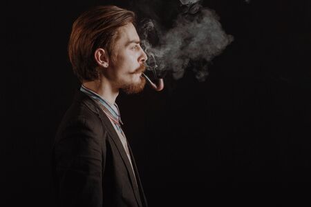 handsome bearded stylish business man in elegant black suit posing in studio on black background,...