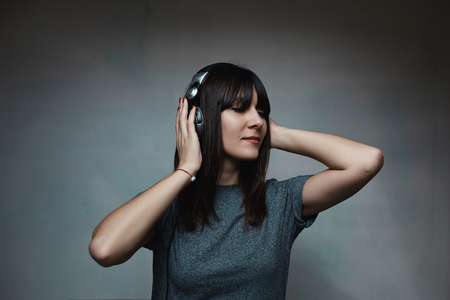 Portrait of pretty brunette woman posing in light room with light from window listening to musicの写真素材