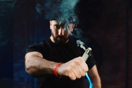 Vaping man wearing a hat, obscured behind a cloud of vapor