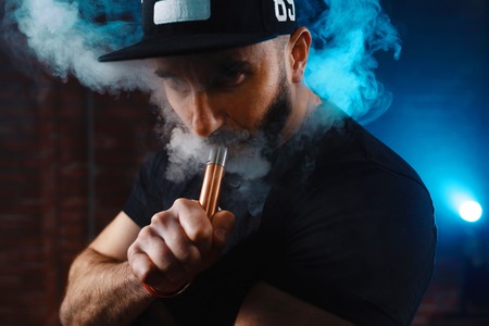 Vaping man wearing a hat, obscured behind a cloud of vaporの写真素材