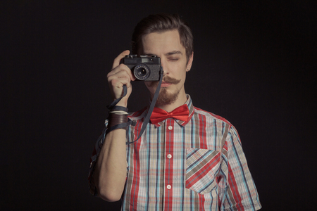 Portrait of bearded hipster wearing red plaid shirt. Holding retro film cameraの写真素材